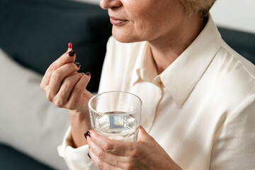 Mature woman prepares to take medication with water for mental health support
