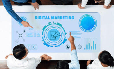 A diverse business team collaboratively strategizing digital marketing initiatives with interactive technology, data graphics, and a focus on innovative solutions in a modern workspace. Trope