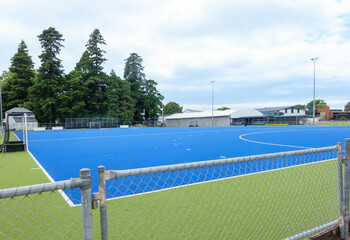 Bright blue astro-turf covered field marked out for sport of hockey.