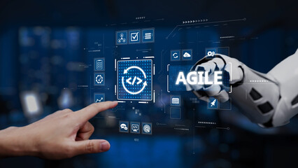 A human hand approaches a robotic arm displaying a digital agile programming interface, symbolizing collaboration between technology and innovation in a modern workspace. Synapse