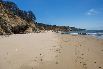 Footprints on a Sandy Beach Leading to Cliffs