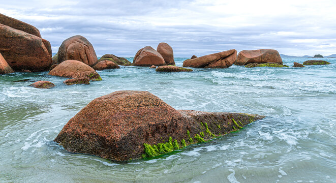 Calm beach with gentle waves and coastal rocks - Powered by Adobe