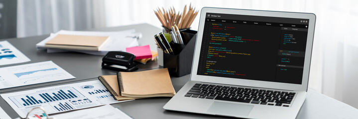 Data analysis dashboard display on laptop screen on office table with financial papers by Fintech BI technology for business marketing and strategy in corporate meeting room. Insight