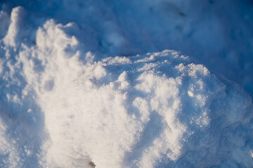 Detailed winter snow mound and drifted snow patterns, close up of bright white surface with icy sparkle and deep blue shadow background outdoors
