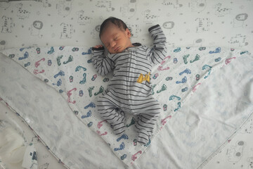 newborn baby laying on patterned blanket