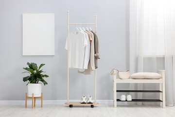 Different clothes hanging on rack, bag and shoes indoors