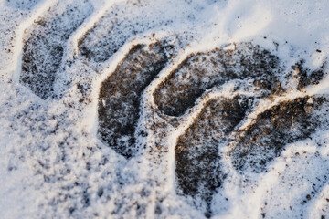 Snow and gravel surface with deep tire track pattern, close up of winter ground texture showing dirty snow, compacted tread grooves and contrast