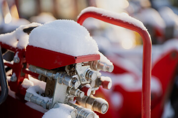Hydraulic hose connections and valve block on red construction machine with snow on top, close up industrial machinery part in cold winter outdoor conditions