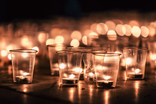 Candlelight vigil with small candles in plastic cups at night, remembrance concept