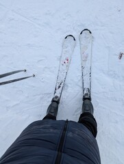 Point of view skiing on a snowy slope with visible skis. Winter sport activity, outdoor recreation, motion and adventure concept.