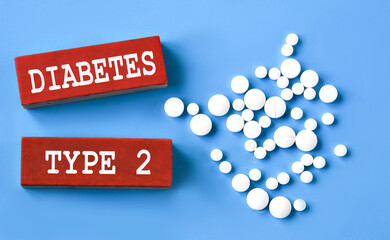 DIABETES TYPE 2 - words on wooden red bars on a blue background with pills