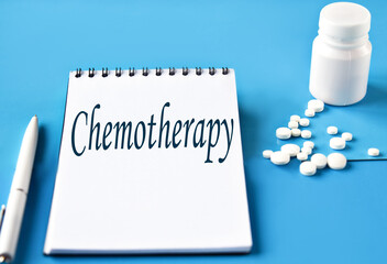 Chemotherapy- word in white notebook on blue background with pills and pen
