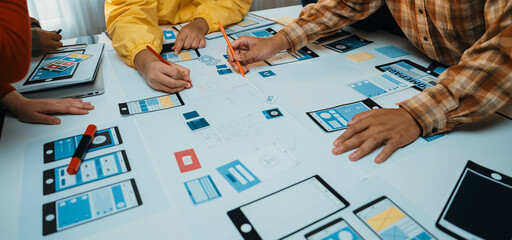 This image captures a vibrant brainstorming session where participants collaborate on designing a mobile app, showcasing sketches, notes, and creative tools on the table. SACTR