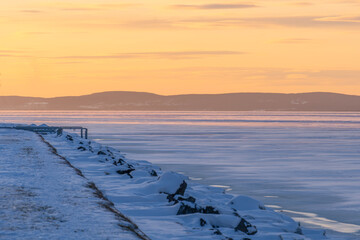 Frozen Lake Balaton with snowy landscape at winter yellow sunset