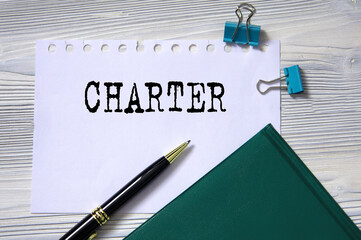 CHARTER - word in white paper on the background of a diary, glasses and pen
