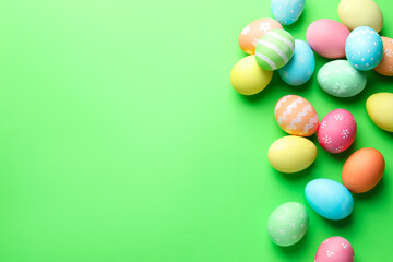 Obraz premium Beautiful decorated Easter eggs on green background, flat lay. Space for text