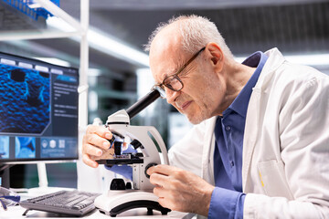 Senior chemist observing specimen under microscope in the laboratory. Clinical experiment illustrates the discovery process in bioscience, pathology and molecular research for innovation.