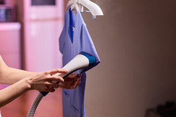 Blue shirt steaming, Blue uniform hanging while expertly steamed for wrinkle removal, Navy blue outfit on hanger being carefully steamed to remove creases professionally