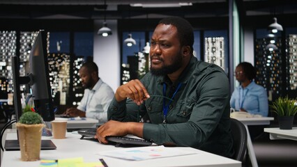 African american analyst wondering about possible solutions to a dilemma on computer, concentration to evaluate projections with logical deduction and intuitive observation at night.
