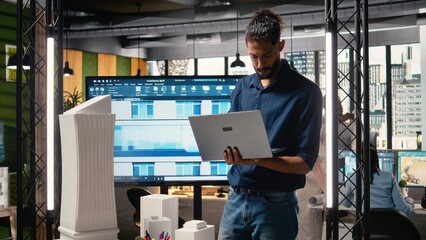 Middle eastern architect reviews blueprints and software for construction master plan, briefing meeting to evaluate measurements and housing layout. Developers with residential project.