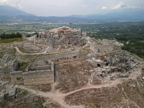 Aerial view of the hilltop citadel and necropolis at tlos near fethiye Layers of ancient walls and chambers Mugla turkiye Farmland and mountain backdrop Good for travel heritage and documentary use