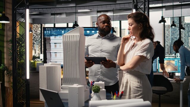 Real estate contractors team creating a modern smart city layout with 3D models architectural blueprints, exchanging ideas for infrastructure growth and residential housing master plan. - Powered by Adobe