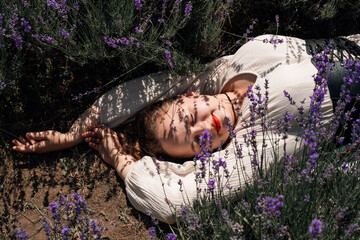 Woman lays in lavender field under sunlight during a clear day