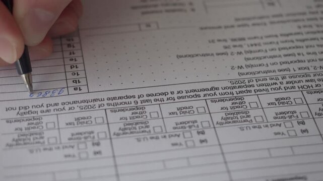 Man Filling In The Tax Form 1040 for 2025 Year. Person Calculates of Planning Budgets Yearly Personal Finance and Fills up US Tax Form 1040 For 2025 Year. Signing 1040 Income Tax Return For 2025 Year.