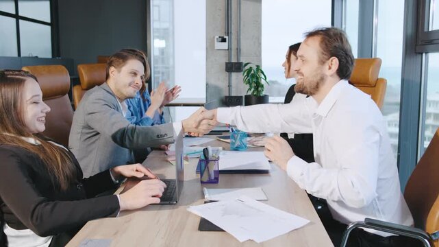 A group of professionals engage in a high-five during a meeting in a business setting that promotes diversity and accessibility.
