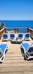 A relaxing terrace with blue sun loungers against the backdrop of the bright blue sea