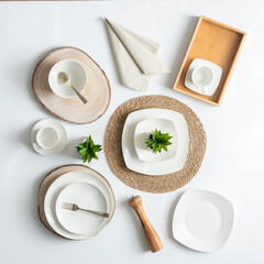 white ceramic plates, bowls, napkins and serving utensils on a wooden table, ready to be used for a...