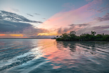 Hermoso amanecer en la laguna de Bacalar Quintana Roo, pintando las nubes de colores anaranjados y...