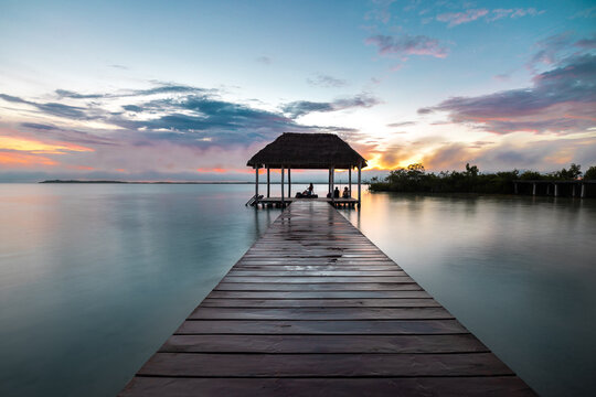 Larga exposici&oacute;n de un hermoso amanecer en un muelle en la laguna de Bacalar, Quintana Roo, M&eacute;xico, contraluz