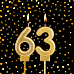 Number 63 birthday candle on a black background with blurred lights