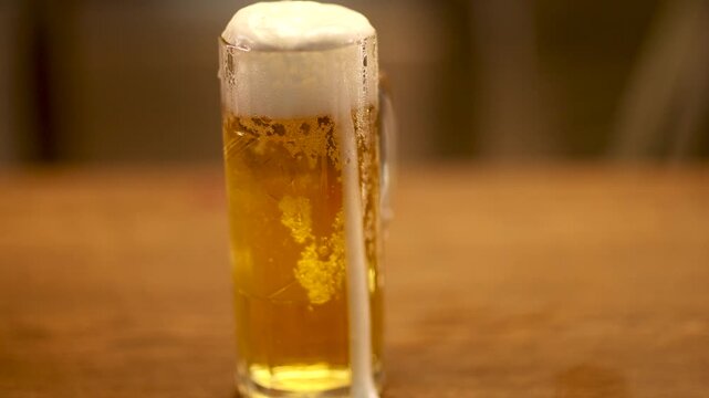 Macro close up of fresh beer foam slowly running down a cold glass, warm light and shallow depth of field