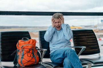 Fototapeta premium Woman sitting in waiting area shows signs of stress at an airport due to flight delays