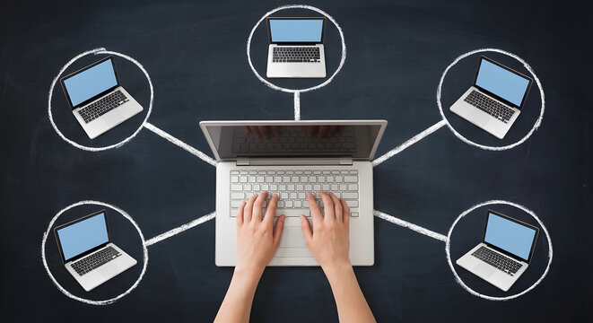 Hands typing on laptop connecting to multiple remote computers in hand drawn chalk circles on blackboard for global networking cloud computing and team collaboration concept - Powered by Adobe