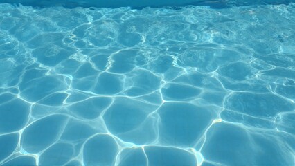 Obraz premium Sparkling blue swimming pool water with sunlight reflecting on the surface creating dynamic patterns