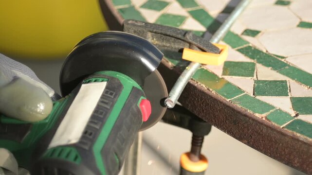 Grinder blade cutting metal rod flashing sparks close-up, side view