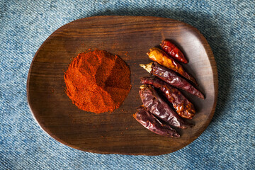 Chili powder and dried red chilies on wooden plate