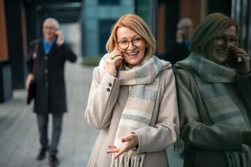 Happy mature woman communicating on smart phone in city