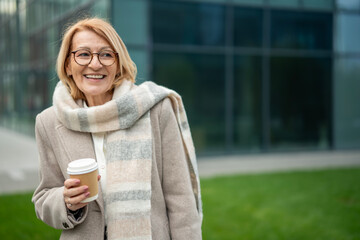 Smiling senior woman enjoying coffee break in city