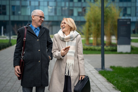 Mature business couple walking outdoor laughing together - Powered by Adobe