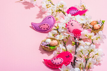 Gentle Easter composition with cherry flowers and handmade felt birds. Decorative eggs and nest