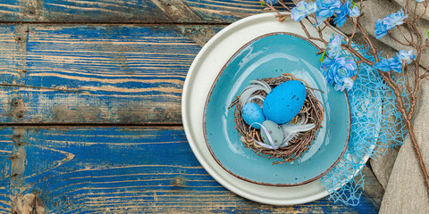 Easter table setting with eggs, bird's nest and blooming branch. Traditional festive symbols