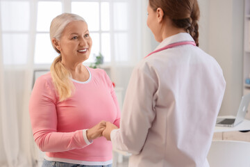 Fototapeta premium Mature woman with gynecologist holding hands in clinic. Menopause concept