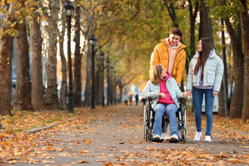 Fototapeta premium Young woman in wheelchair with her friends on autumn day