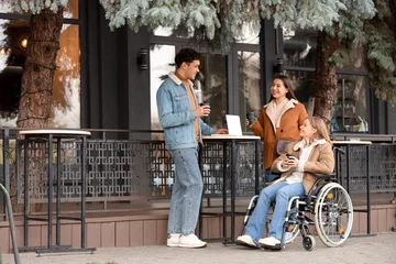 Fototapete Altes Krankenhaus Beelitz Young woman in wheelchair and her friends with coffee at street cafe  © Pixel-Shot