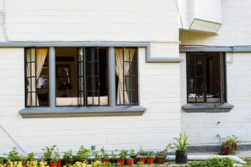 White Brick Cottage Wall with Open Windows and Potted Plants