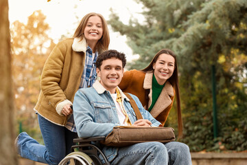 Fototapeta premium Young man in wheelchair with his friends outdoors
